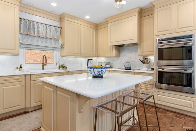 kitchen with black electric stovetop, a kitchen island, sink, a breakfast bar area, and double oven