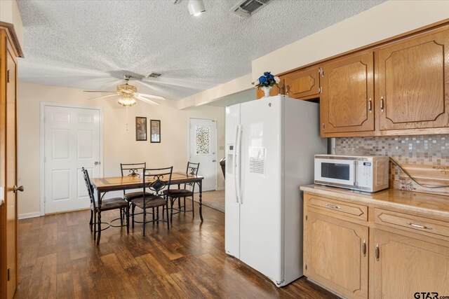 kitchen featuring a ceiling fan, a textured ceiling, white appliances, visible vents, and dark wood-type flooring