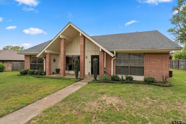 mid-century home featuring board and batten siding, brick siding, a front lawn, and fence