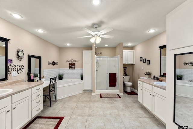 bathroom featuring a bath, a stall shower, a ceiling fan, and two vanities