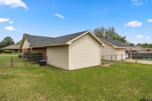 view of side of property featuring a lawn, fence, central AC, roof with shingles, and a gate