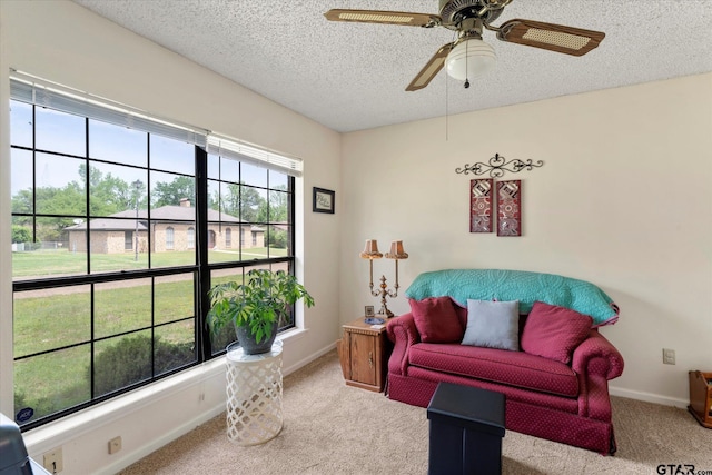 sitting room with a textured ceiling, a wealth of natural light, ceiling fan, and carpet