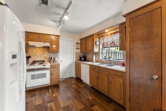 kitchen with a sink, dark wood-type flooring, white appliances, under cabinet range hood, and light countertops