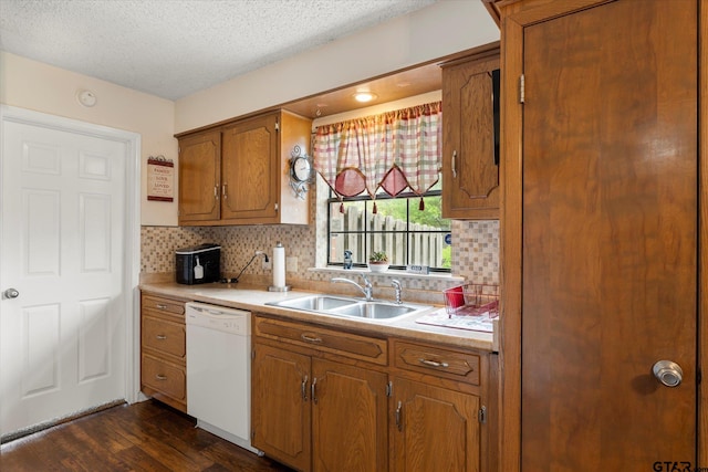 kitchen with a sink, brown cabinetry, backsplash, light countertops, and white dishwasher