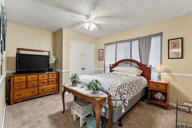 carpeted bedroom with a textured ceiling, baseboards, and a ceiling fan