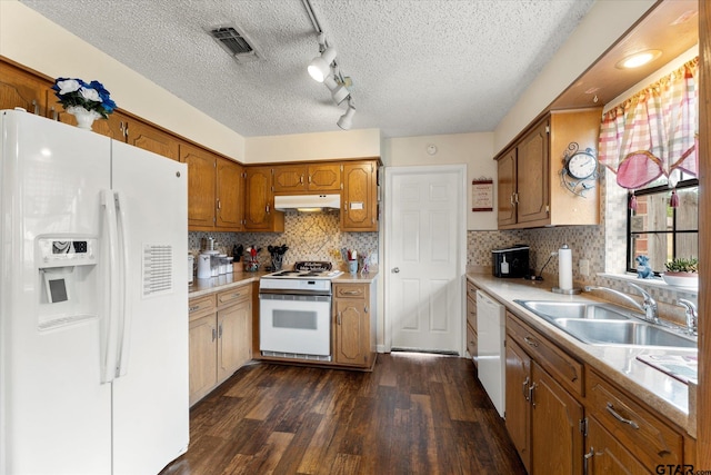 kitchen featuring under cabinet range hood, dark wood-style flooring, white appliances, visible vents, and a sink