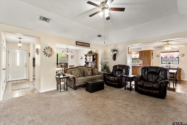 living room featuring light carpet, visible vents, ceiling fan, and a textured ceiling