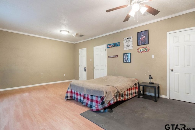 bedroom featuring baseboards, ornamental molding, wood finished floors, and visible vents