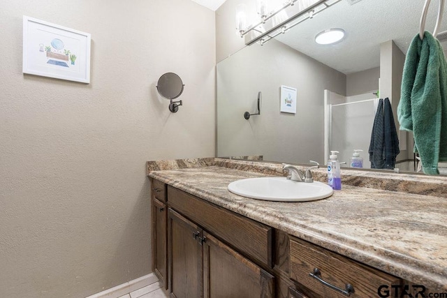 full bathroom with vanity, baseboards, tile patterned floors, and a shower stall