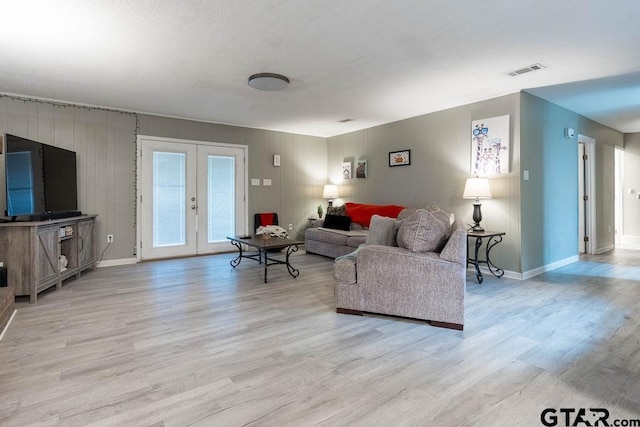 living room featuring baseboards, visible vents, french doors, and light wood finished floors