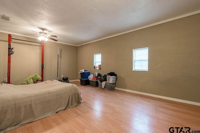 bedroom with a textured ceiling, visible vents, crown molding, baseboards, and light wood-style floors