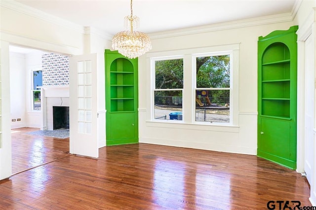 unfurnished living room with a notable chandelier, built in features, dark hardwood / wood-style floors, and ornamental molding