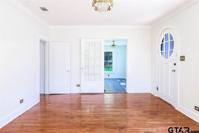 foyer entrance with hardwood / wood-style flooring, a notable chandelier, and crown molding