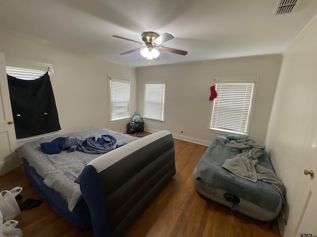 bedroom with visible vents, ceiling fan, baseboards, and wood finished floors