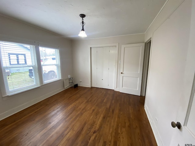 unfurnished bedroom with baseboards, dark wood finished floors, and a closet