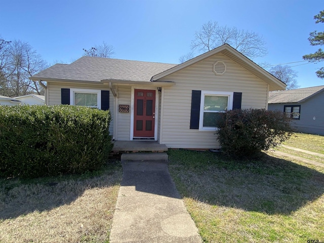 view of front facade featuring a front lawn and roof with shingles