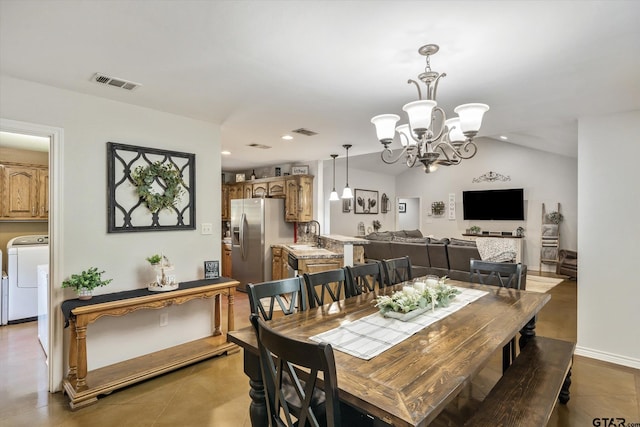 tiled dining area featuring washer / dryer, a chandelier, sink, and lofted ceiling