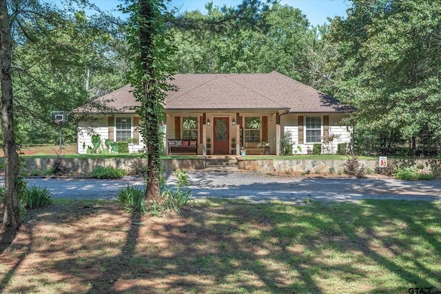 ranch-style home featuring covered porch and a front yard