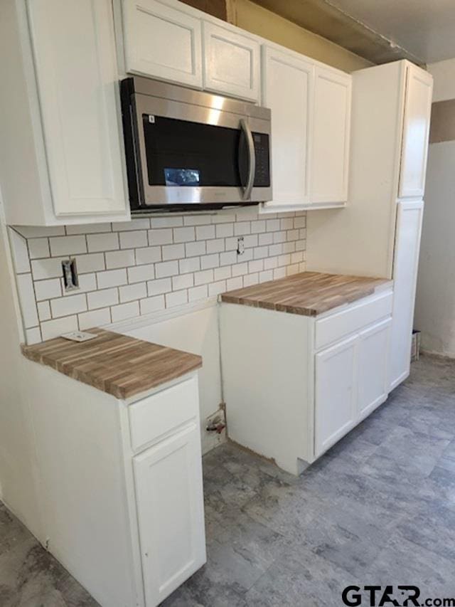 kitchen with decorative backsplash, white cabinetry, and wooden counters