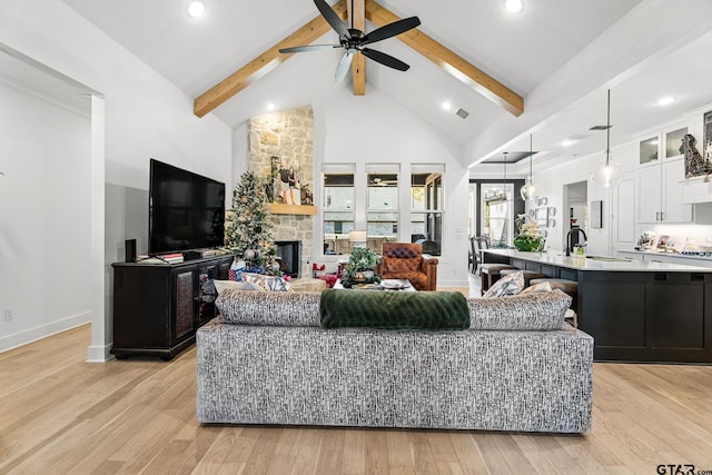 living room featuring beam ceiling, light wood-type flooring, ceiling fan, and sink