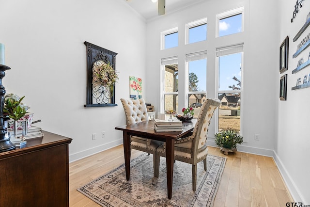 dining room featuring a towering ceiling, light hardwood / wood-style flooring, ceiling fan, and crown molding