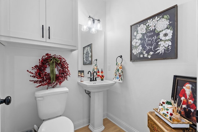 bathroom featuring toilet, wood-type flooring, and sink