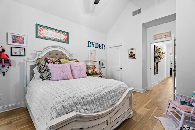 bedroom with hardwood / wood-style flooring, ceiling fan, and high vaulted ceiling