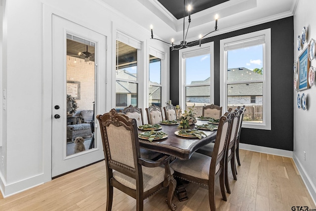 dining room featuring a chandelier, ornamental molding, a tray ceiling, and light hardwood / wood-style flooring