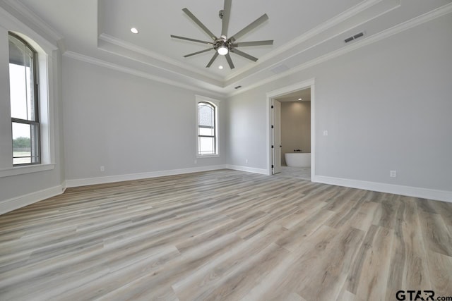 spare room with ceiling fan, a raised ceiling, light wood-type flooring, and crown molding