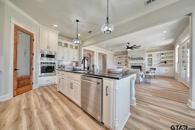 kitchen with pendant lighting, a kitchen island with sink, white cabinets, sink, and stainless steel appliances