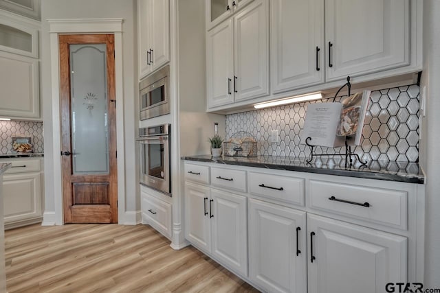 kitchen featuring white cabinets, light wood-type flooring, stainless steel appliances, and tasteful backsplash