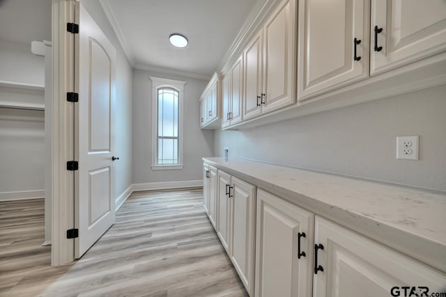 clothes washing area featuring cabinets, washer hookup, light wood-type flooring, and ornamental molding