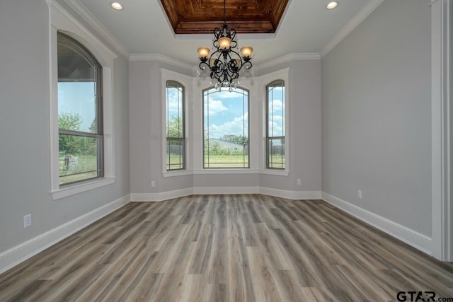 spare room featuring hardwood / wood-style floors, a notable chandelier, a raised ceiling, and crown molding