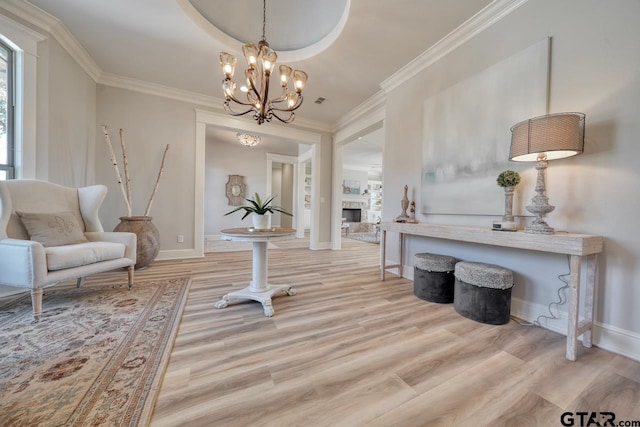 living area featuring crown molding, light hardwood / wood-style floors, and an inviting chandelier