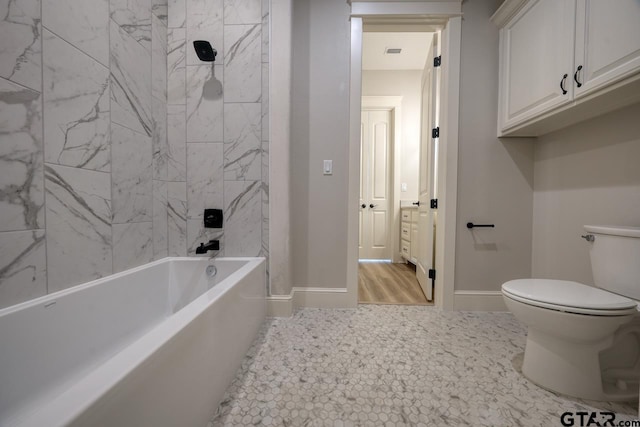 bathroom featuring tiled shower / bath combo, hardwood / wood-style flooring, and toilet