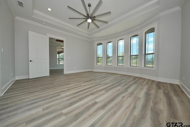 spare room with a tray ceiling, ceiling fan, crown molding, and light hardwood / wood-style floors