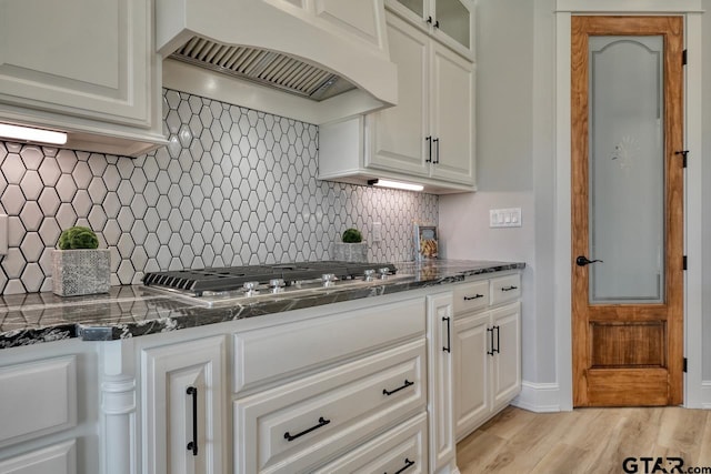 kitchen featuring decorative backsplash, white cabinets, light wood-type flooring, and custom exhaust hood