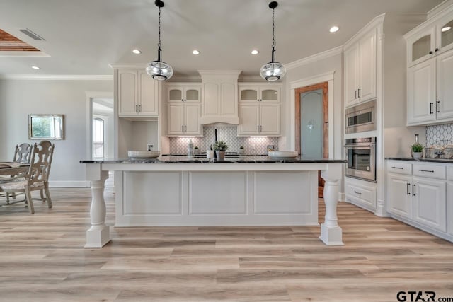 kitchen with crown molding, stainless steel appliances, decorative light fixtures, and light hardwood / wood-style floors