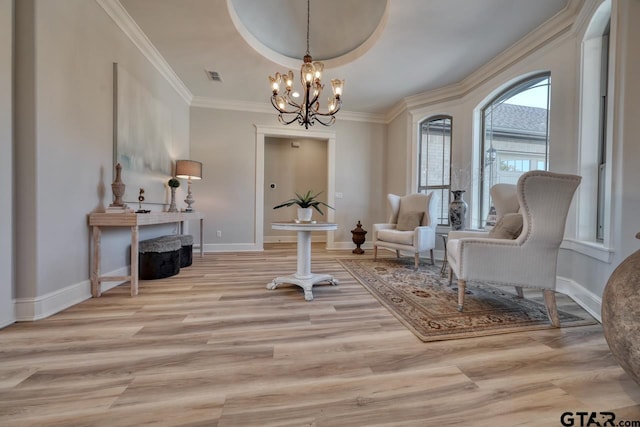 sitting room with an inviting chandelier, a raised ceiling, crown molding, and light hardwood / wood-style flooring