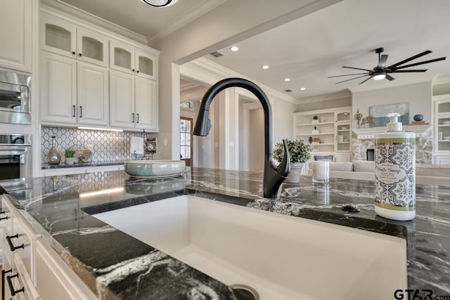 kitchen with white cabinets, sink, dark stone countertops, ornamental molding, and stainless steel appliances