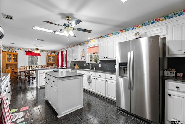 kitchen featuring white cabinetry, stainless steel refrigerator with ice dispenser, a center island, and kitchen peninsula