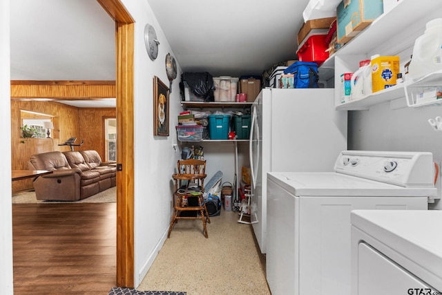 clothes washing area featuring washer and dryer and wood walls