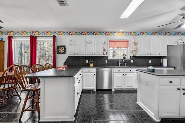 kitchen with a breakfast bar area, ceiling fan, dishwasher, white cabinetry, and a kitchen island