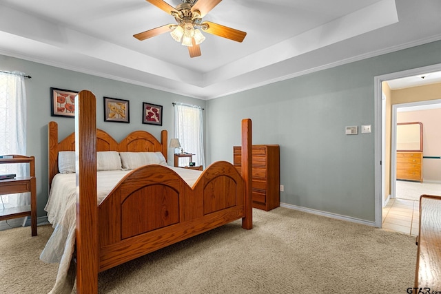 bedroom with ceiling fan, ornamental molding, a raised ceiling, and light colored carpet