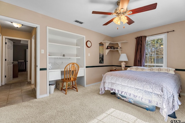 carpeted bedroom with built in desk and ceiling fan