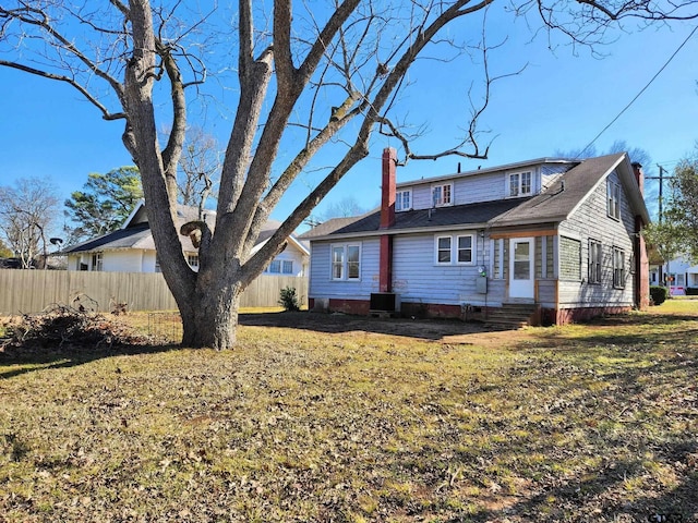 back of house with central AC unit and a yard