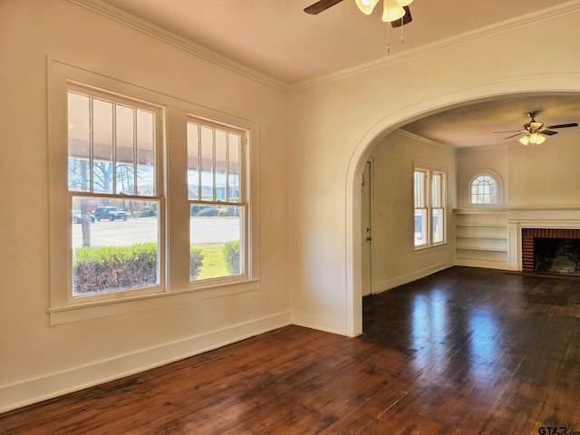 501 E Park Ave, Palestine, TX 75801 - unfurnished living room featuring a ceiling fan, ornamental molding, dark wood-type flooring, baseboards, and arched walkways