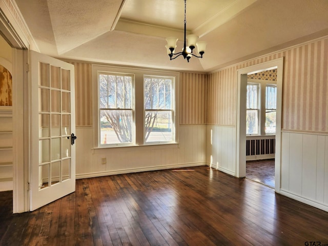 spare room featuring dark hardwood / wood-style floors, a textured ceiling, a chandelier, a raised ceiling, and crown molding