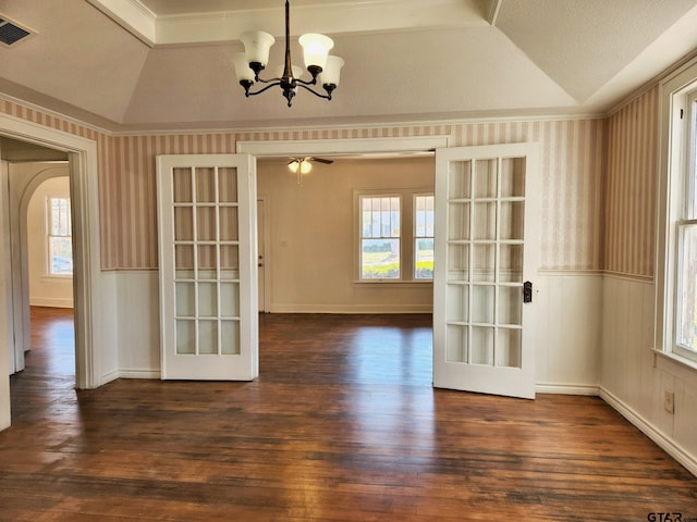 unfurnished dining area with dark wood-type flooring, french doors, ceiling fan with notable chandelier, and vaulted ceiling