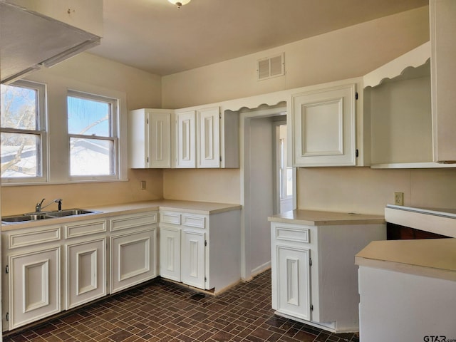501 E Park Ave, Palestine, TX 75801 - kitchen with a sink, light countertops, white cabinets, and brick patterned floors